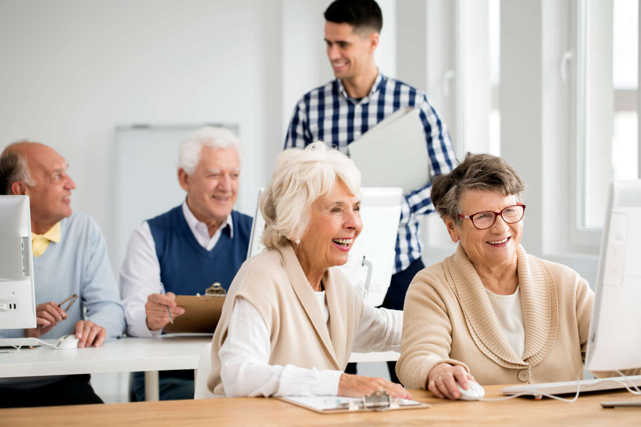 Two older adults sitting together and using a laptop